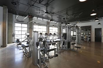 Fitness center with various strength and cardio machines, concrete flooring
